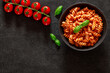 Fusilli, cooked pasta with tomato sauce, tomatoes cherry and basil leaf, on dark background, top view, space to copy text.