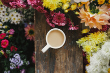 Good Fall Morning. Warm Cup Of Coffee And Beautiful Autumn Flowers On Rustic Wooden Background Flat Lay. Stylish Mug With Cappuccino Among Colorful Asters And Dahlias Composition.
