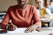 © Seventyfour - Closeup African American young woman taking notes while studying at desk in college classroom