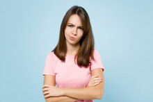 Young Sad Disappointed Displeased Caucasian Woman 20s Wear Pink T-shirt Look Camera Hold Hands Crossed Folded Isolated On Pastel Plain Light Blue Background Studio Portrait. People Lifestyle Concept.
