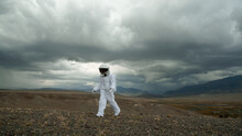 An Astronaut Explores An Unknown Planet. Heavy Cloudy Sky.