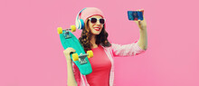 Summer Colorful Portrait Of Stylish Modern Young Woman Taking A Selfie By Smartphone With Skateboard And Headphones On Pink Background