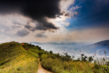 Wall Mural - Natural landscape narrow path on a mountain peak with grass, and mountain scape in the background