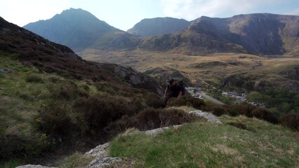 Canvas Print - A hiker climbing high into the mountains of Snowdonia North Wales with large backpack and tripod