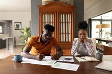 Serious African American Young Man Analyzing Bills With Girlfriend On Table While Sitting At Home