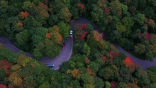 Aerial Drone Footage, Looking Down Over Beautiful Fall Foliage Starting To Change Colors, As A Windy Road Weaves It's Way Through This Forest Of New England.