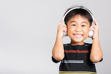 Little Cute Kid Boy 5-6 Years Old Listen Music Wear Wireless Headphones In Studio Shot Isolated On White Background, Happy Asian Children Holding Headset Smiling Listening Audio, Entertainment Concept