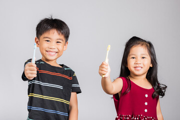 Little cute kid boy and girl 3-6 years old show brush teeth and smile in studio shot isolated on white background, Asian children holding toothbrush in mouth by himself, Dental hygiene healthy concept