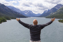 Bald Adult Man Raising His Hands Sideward At The Waterton Lake In Alberta, Canada