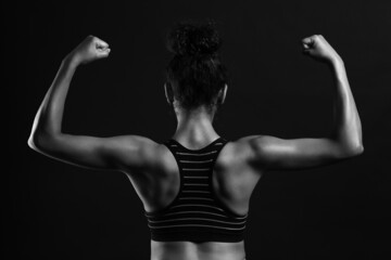 Black and white photo of sporty young African-American woman on dark background