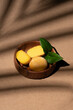 Mochi ice cream on light background. Mango fruit dessert in a wooden bowl. Traditional japanese sweets. Tropical, sunny poster with palm leaves shadow. Summer vibe. Vertical, close up, selective focus