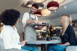 © nenetus - Handsome waitress man serving coffee and pastry for smiling women in the table in a pastry shop.