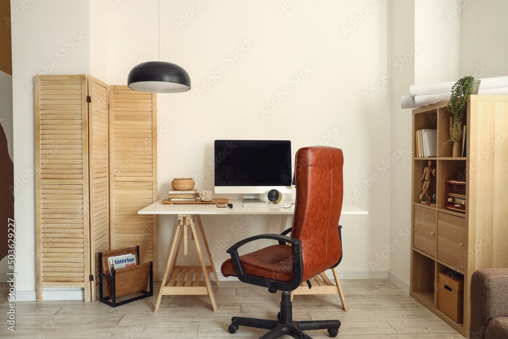 Comfortable workplace near light wall in room interior