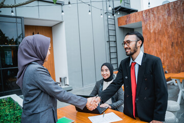 Wall Mural - asian muslim businesswoman shaking hand with partner at the office during meeting