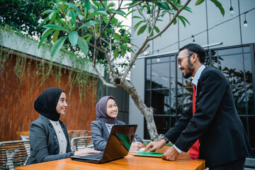 portrait of businessman at meeting with his two female muslim employee