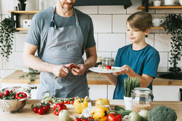 family dad young man and son teenage boy cook vegetable salad in kitchen and spend quality time together, father and son talking and cooking vegetarian food and doing chores, 8 march and mothers day