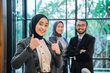 Business Muslim Woman Showing Thumb Up To Camera With Partner At The Background Smiling