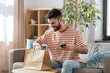 © Syda Productions - communication, leisure and people concept - happy smiling man using smartphone for takeaway food order check up at home
