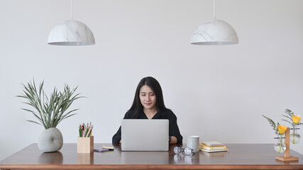 Wall Mural - Beautiful asian woman using laptop computer at modern home office.