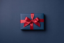 Blue Gift Box Tied Red Ribbon On Dark Blue Background.