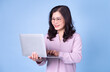 © Timeimage - Portrait of middle aged Asian woman using laptop on blue background