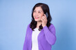 © Timeimage - Portrait of middle aged Asian woman using smartphone on blue background
