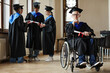 © Seventyfour - Full length portrait of young man with disability at graduation ceremony in university, copy space