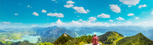 Woman Sitting And Relaxing At Top Of Mountain Herzogstand After Hiking. Looking At The Spectacular Bavarian Prealps Mountains Panorama With Lakes (Kochelsee, Walchensee) Europe, Germany