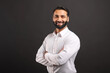 © Vadim Pastuh - Proud Indian male businessman in white smart casual shirt stand with arms crossed isolated on black background, successful hispanic male entrepreneur in confident pose
