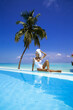 © marcink3333 - Elegant tanned woman in white swimsuit in pool on tropical Maldives island. Beautiful bikini body girl in pool with view on horizon. Sexy model near the pool on beautiful Indian ocean landscape.