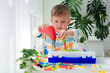 Little boy playing set with a screwdriver and a drill,  and screws and parts . The child plays builder with a toy drill to develop imagination and motor skills. Educational logic toys for children.