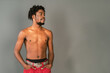 © Svyatoslav Lypynskyy - Shirtless african male model standing half turn with hands in pockets. Half naked african american man posing on camera isolated on grey background. Topless african american man