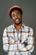 © Svyatoslav Lypynskyy - Young smiling black man in afro hat standing with arms folded looking at camera. Cheerful african american young man in plaid shirt looking at camera isolated on gray background
