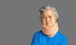 Portrait of a senior woman wearing a soft neck collar because suffering neck pain and neck tilt while standing on a gray background