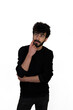 © enver - Curly haired young male in black sweater stands thoughtfully with one hand on chin. Isolated on white background