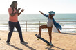 © Wavebreak Media - African american father cheering son showing off skateboarding skill on promenade at sunny day