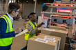 © Wavebreak Media - Asian manager with checklist looking at african american young man scanning barcode on cardboard box