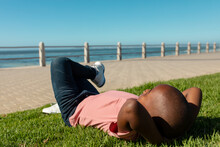 Full Length Of African American Boy Relaxing While Lying On Grass At Promenade During Sunny Day
