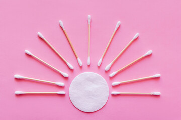 Wall Mural - flat lay of ear sticks around white cotton pad on pink background, top view.