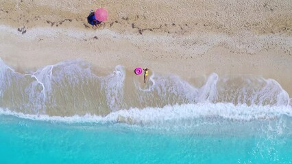 Poster - Aerial view of young woman with pink swim ring on the sandy beach
