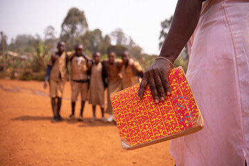 an african teacher is holding a book with her students out of focus in the background, concept of ed