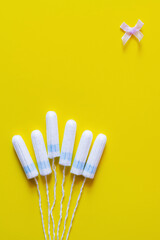 Wall Mural - top view of tampons and bow on yellow background with copy space.