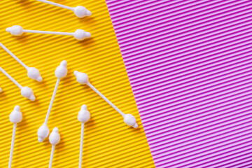 Wall Mural - top view of hygienic ear sticks on yellow and violet textured background.