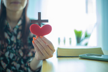 Wall Mural - Wooden cross and red heart in female hand with love and religion concept.