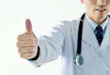 Closeup Of Male Doctor Showing Thumbs Up Against White Background