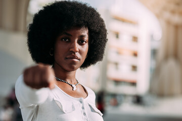 portrait of a young black woman with afro hair gesturing with her clenched fist symbolizing strength