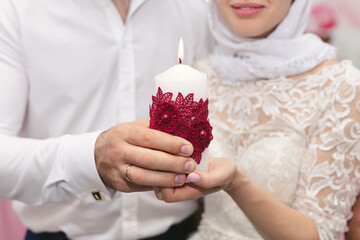 Canvas Print - A candle in the hands of the newlyweds. Ignition of the family hearth at the wedding