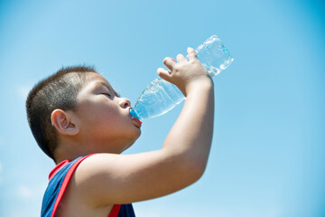  Little asian boy drinking water against blue sky