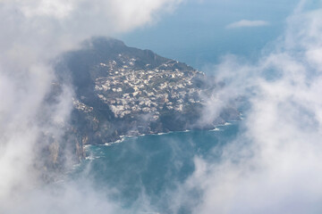 Panoramic view from Monte Comune on the coastal town Positano appearing from clouds. Magical hiking above thick fog in Lattari Mountains, Apennines, Amalfi Coast, Campania, Italy, Europe. Misty vibes