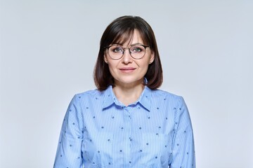 Wall Mural - Portrait of business mature woman looking at camera on light studio background